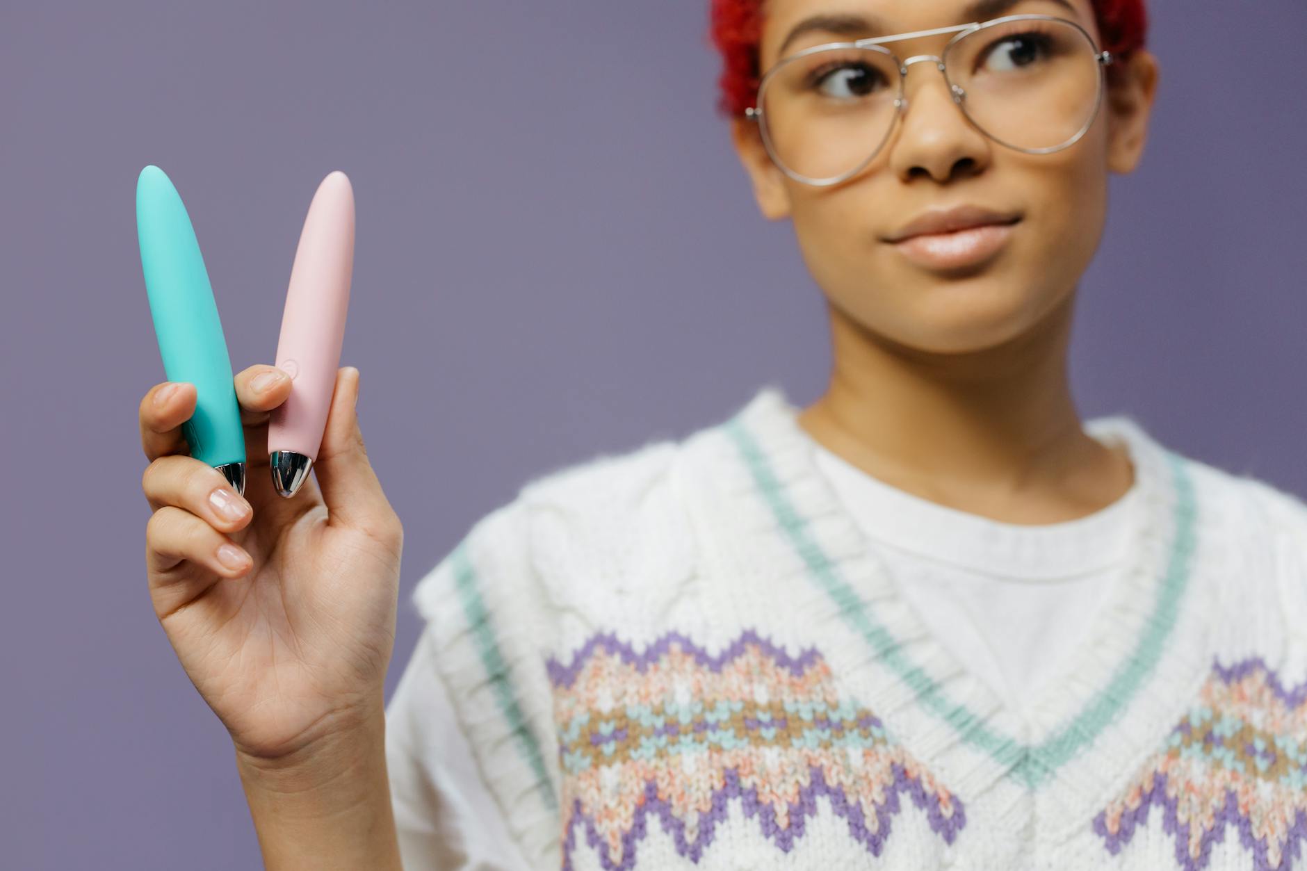 Woman holding two colorful vibrators with curiosity and gentle confidence