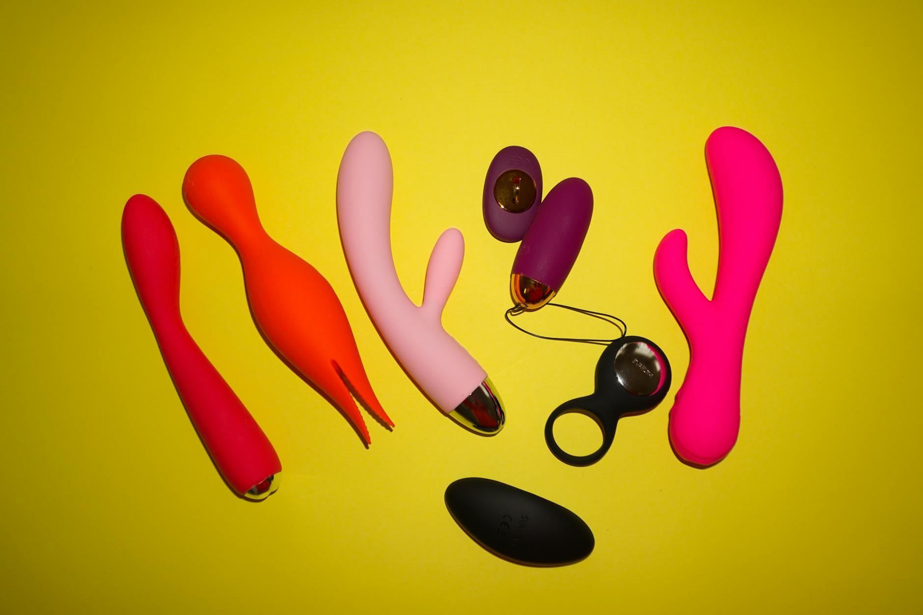 Woman holding colorful clitoral vibrators against purple background